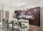 Thumbnail 3 of 26 - A kitchen with a granite countertop and green chairs.