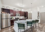 Thumbnail 4 of 26 - A kitchen with a marble countertop and green chairs.