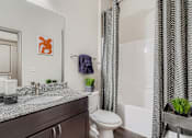 Thumbnail 5 of 26 - A bathroom with a toilet, sink, and shower curtain.