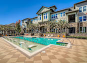 Thumbnail 17 of 26 - A large swimming pool in front of a building with a tiled floor.
