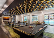 Thumbnail 16 of 35 - Spacious resident game room featuring a pool table, poker table, lounge seating, and entertainment amenities.