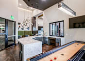 Thumbnail 18 of 35 - Resident lounge featuring a shuffleboard table, comfortable seating, and modern clubhouse amenities.