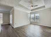 Thumbnail 13 of 32 - A spacious room with wooden floors and a ceiling fan.