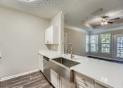 Thumbnail 8 of 32 - A kitchen with a stainless steel sink and white cabinets.