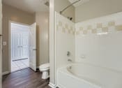 Thumbnail 30 of 32 - A white bathroom with a tub, toilet and sink.