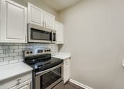 Thumbnail 28 of 32 - A kitchen with white cabinets and a black stove top oven.
