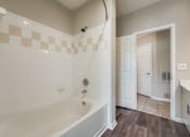 Thumbnail 26 of 32 - A bathroom with a tub and a doorway leading to another room.