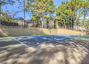 Thumbnail 15 of 32 - A tennis court surrounded by trees and apartment buildings.