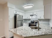 Thumbnail 13 of 37 - A kitchen with granite countertops and white cabinets.