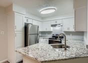 Thumbnail 17 of 37 - A kitchen with granite countertops and white cabinets.