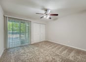 Thumbnail 20 of 37 - A room with a ceiling fan and carpeted floor.