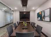 Thumbnail 23 of 35 - Modern on-site conference room with large meeting table, executive chairs, and wall-mounted display screen.