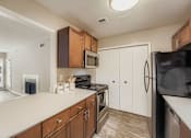 Thumbnail 15 of 39 - A kitchen with brown cabinets and a black refrigerator.