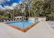 Thumbnail 19 of 39 - A large outdoor swimming pool surrounded by trees and lounge chairs.