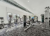 Thumbnail 21 of 39 - A spacious gym with a variety of equipment including treadmills, stationary bikes, and weight machines.