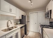 Thumbnail 8 of 39 - A kitchen with white cabinets and a black refrigerator.