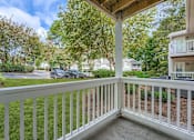 Thumbnail 33 of 39 - A white railing leads to a covered deck with a view of a tree-lined street.