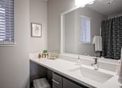 Thumbnail 10 of 26 - A bathroom with a white sink and a mirror.