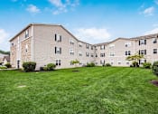 Thumbnail 26 of 28 - A large apartment complex with a green lawn in front.