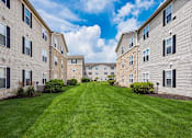 Thumbnail 27 of 28 - A grassy courtyard is surrounded by apartment buildings.
