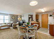 Thumbnail 31 of 40 - A well-lit, clean, and organized living room with a dining area and kitchen in the background.