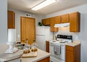 Thumbnail 29 of 40 - A kitchen with wooden cabinets and a white stove top oven.