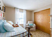 Thumbnail 33 of 40 - A bedroom with a bed, chair, and wooden door.