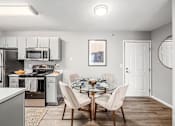 Thumbnail 4 of 28 - A modern kitchen with a glass dining table set for four.