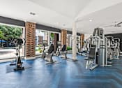 Thumbnail 17 of 38 - A gym with a variety of equipment including treadmills, weights, and a rowing machine.