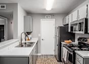 Thumbnail 2 of 28 - A kitchen with a white sink and black stove.