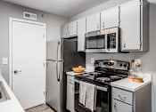 Thumbnail 1 of 28 - A kitchen with a stove, refrigerator, and microwave.