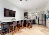 Thumbnail 17 of 26 - A kitchen with a white counter top and brown chairs.