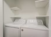 Thumbnail 13 of 26 - Two white washing machines in a small laundry room.