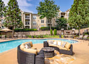 Thumbnail 19 of 32 - A poolside patio with a couch and a table.