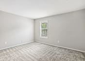 Thumbnail 12 of 39 - A room with a carpeted floor and a window with blinds.