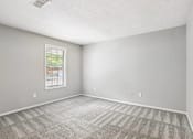 Thumbnail 13 of 39 - A room with a window and carpeted floor.