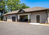 Thumbnail 15 of 26 - A small building with a garage door and a covered entrance.