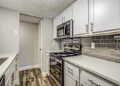 Thumbnail 10 of 20 - A kitchen with a stove top oven and microwave above it.