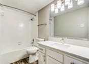 Thumbnail 15 of 20 - A white bathroom with a toilet, sink, and mirror.