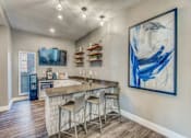 Thumbnail 10 of 38 - A kitchen with a bar area and a painting on the wall.