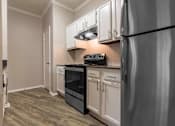 Thumbnail 29 of 38 - A kitchen with a black fridge and white cabinets.