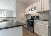 Thumbnail 28 of 38 - A modern kitchen with white cabinets and a black countertop.