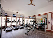 Thumbnail 3 of 24 - A gym with treadmills, exercise bikes, and a fan.