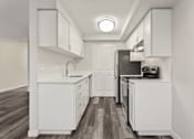 Thumbnail 11 of 24 - A modern kitchen with white cabinets and dark wood floors.