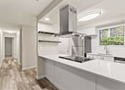Thumbnail 4 of 24 - A modern kitchen with a stainless steel range hood and white countertops.