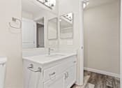 Thumbnail 13 of 24 - A white bathroom with a sink, mirror, and toilet.
