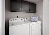 Thumbnail 22 of 23 - A white washing machine and dryer in a small laundry room.