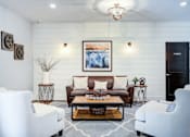 Thumbnail 18 of 23 - A living room with a white sofa, two white chairs, and a coffee table.