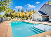 Thumbnail 2 of 23 - A swimming pool in front of a house with trees in the background.