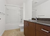 Thumbnail 10 of 32 - A white toilet sits in a bathroom with a sink and a shower.